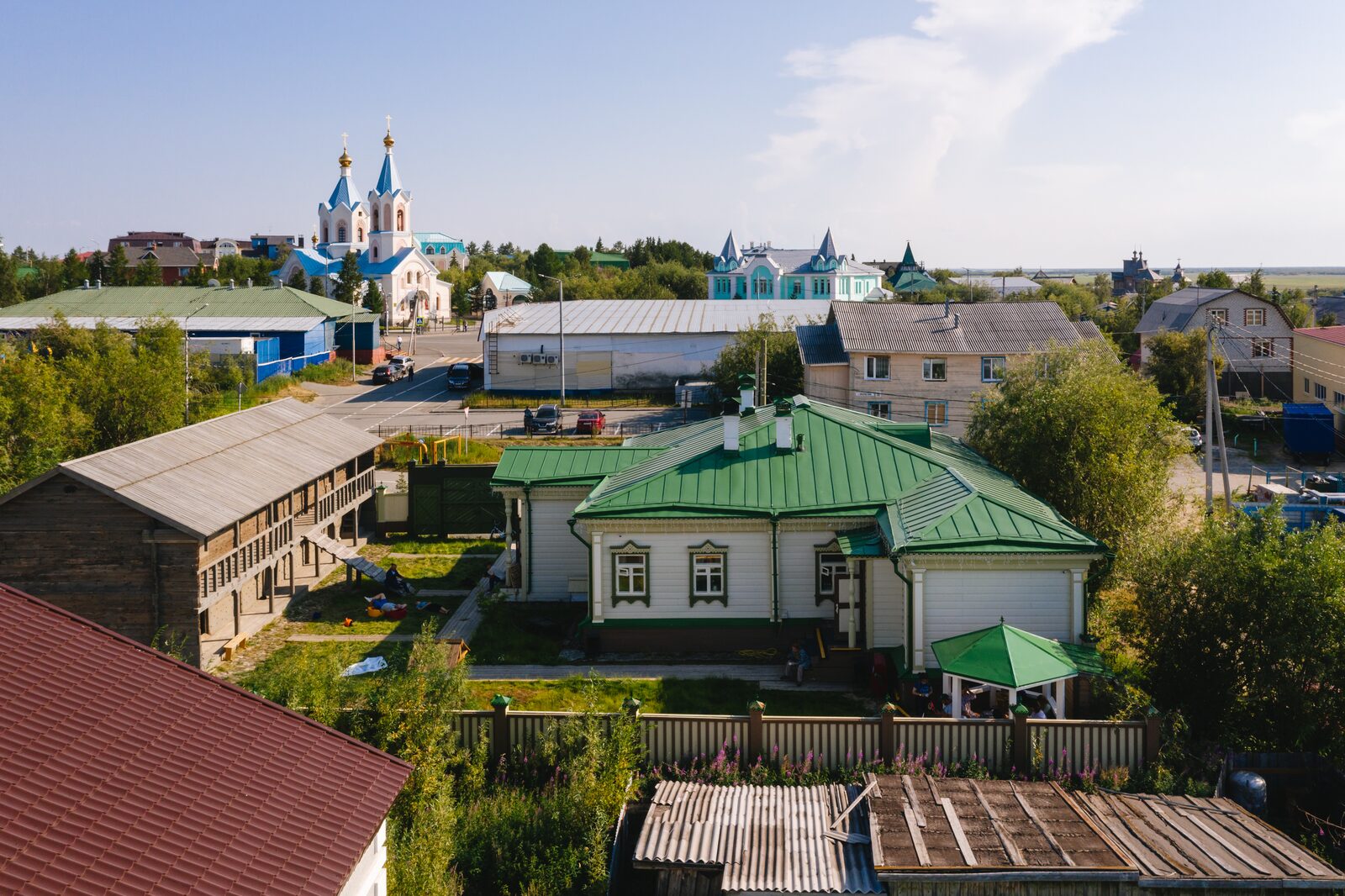 Салехард, старая часть города — деревянная усадьба с зелёной крышей, вдали храм